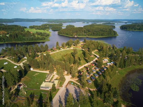 Aerial view of blue lake and green forests on a sunny summer day above a caravan camping site. Bird's eye view drone photography. Ruovesi, Finland. photo