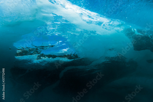 Wave with bubbles underwater. Transparent blue ocean in underwater