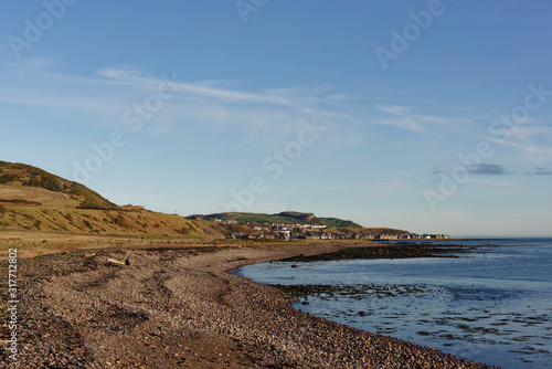 The small Coastal town of Gourdon seen from the steeply shelving Shingle Beach at Benholm on the East Coast of Scotland.