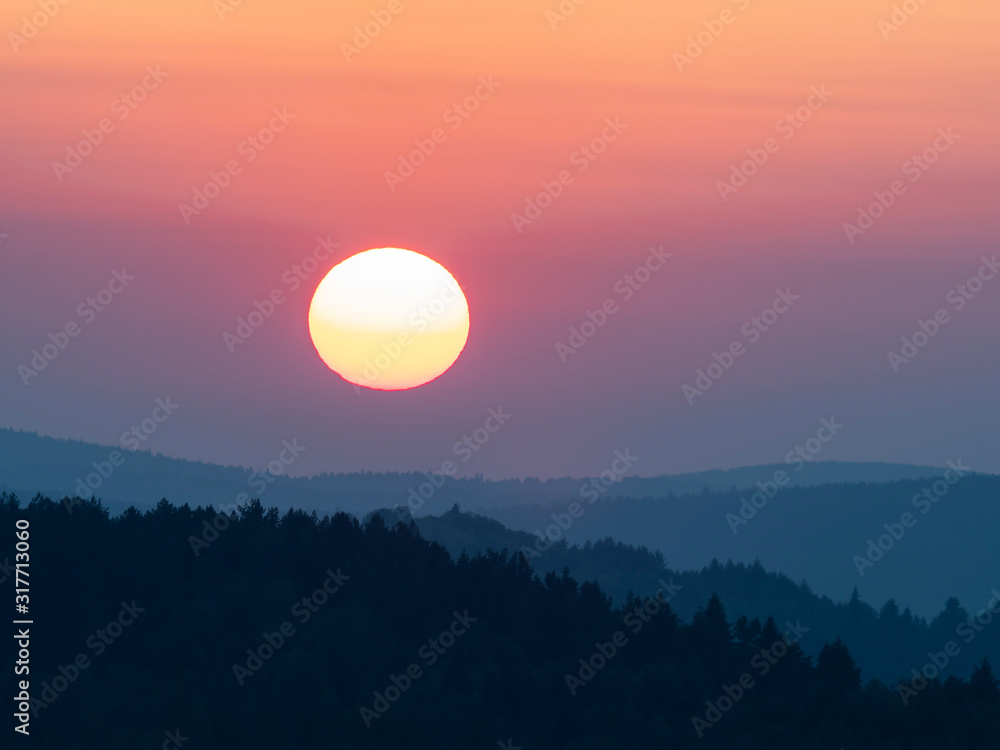 Sunset in the mountains with full disk of sunset under the horizon. Magical sunset in the Carpathians, orange sky, full disk of sunset. 