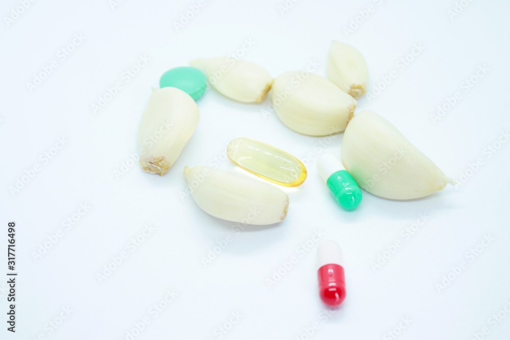 Garlic cloves and tablets located on a white background Garlic cloves and tablets located on a white background