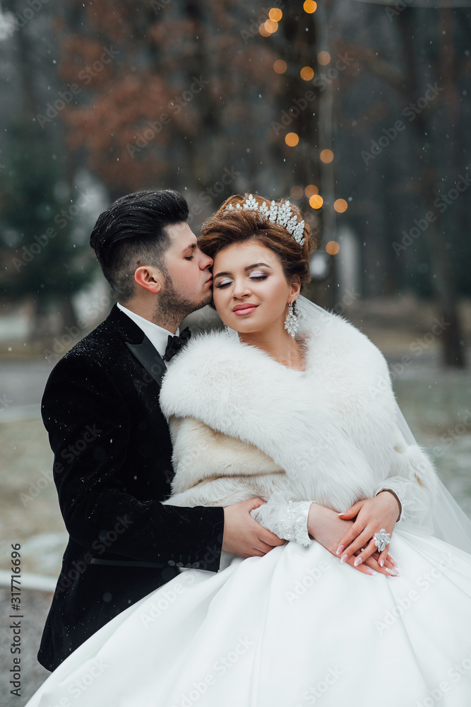 Winter wedding. Beautiful couple on their wedding day. Romantic atmophere on the wedding. Bride and groom in love. The best day of a young couple. Sensual and tender bride and groom outdoors Winter wedding. Beautiful couple on their wedding day. Romantic atmophere on the wedding. Bride and groom in love. The best day of a young couple. Sensual and tender bride and groom outdoors