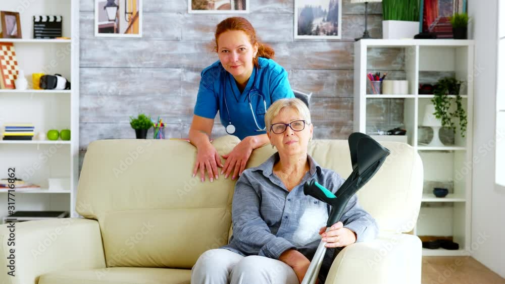 Pretty nurse in nursing home and old woman sitting on couch Pretty nurse in nursing home and old woman sitting on couch