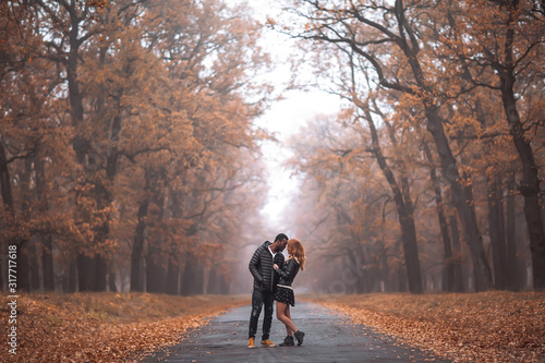 Interracial couple posing in autumn park road