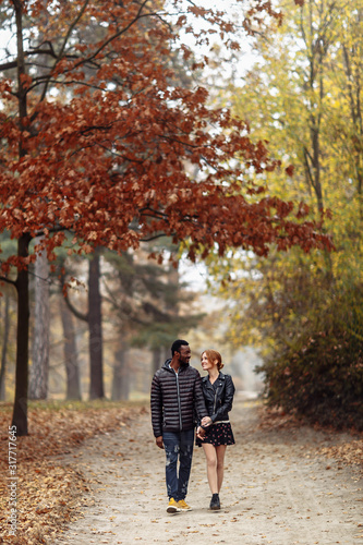 Happy interracial couple walking in autumn park © onphotoua