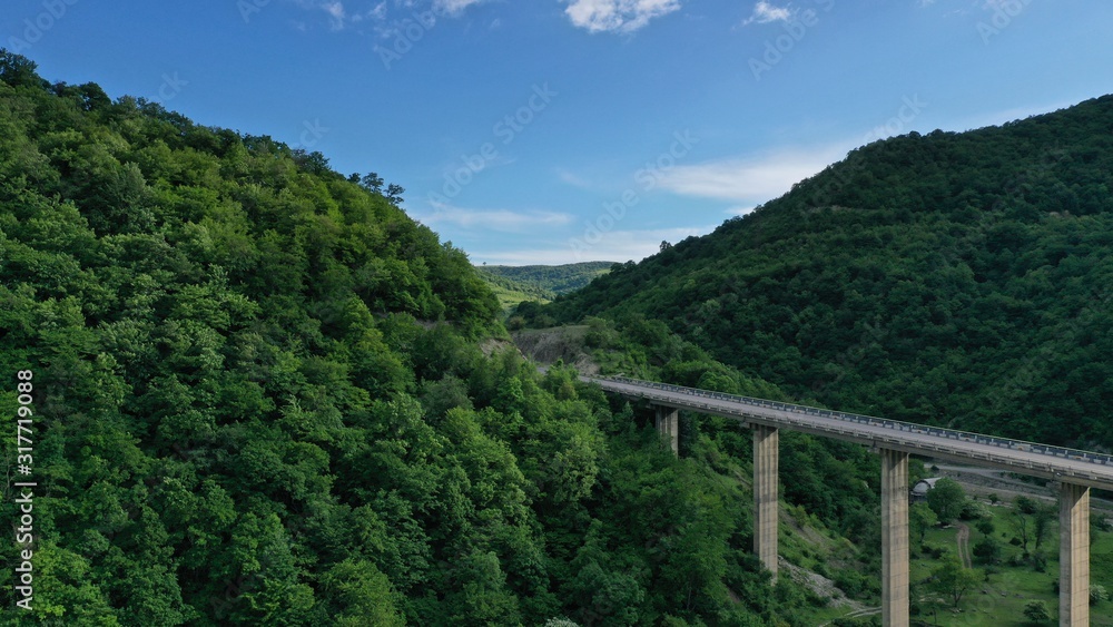 Aerial view of bridge over Aragvi river near Ananuri Fortress and Church. Mountain landscape. Summer. Green trees. Cars going on bridge road. Georgia.