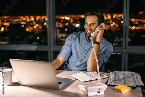 Smiling businessman working at his office desk late at night © marvent