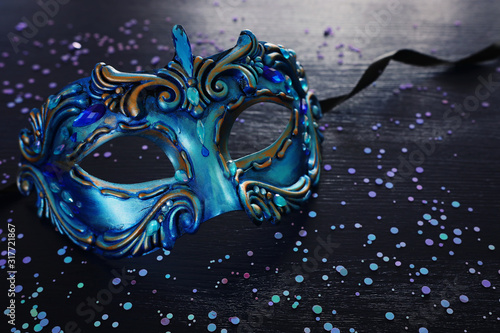Photo of elegant and delicate blue Venetian mask over dark wooden background