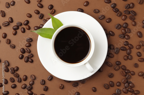 Coffee beans and a cup of coffee on a brown color background. Top view. Place for text.