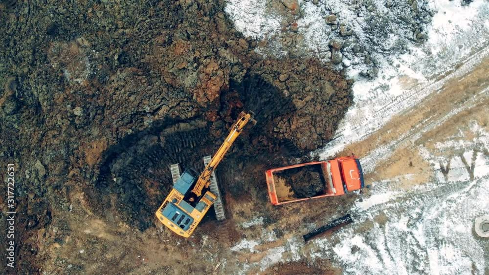 Excavating machine is loading soil into the track Excavating machine is loading soil into the track