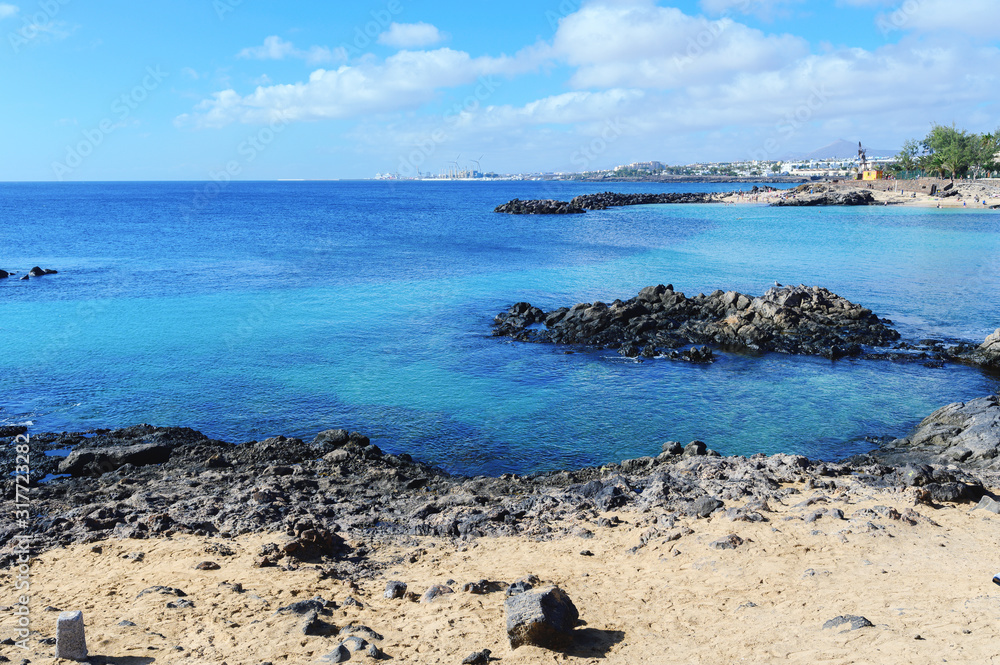 Lagoon with turquoise clear water in Playa Jablillo beach, in Costa Teguise, Lanzarote, Canary islands. Sandy beach with blue sea, volcanic rocks