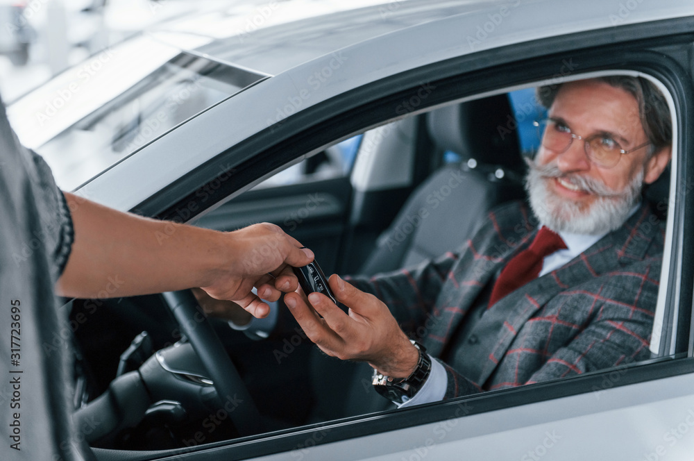 Naklejka premium Modern stylish senior man with grey hair and mustache is in the modern car