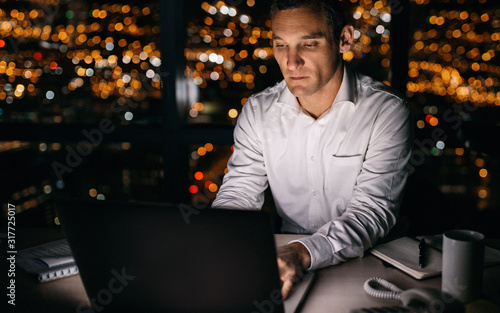 Young businessman working late at night on a laptop