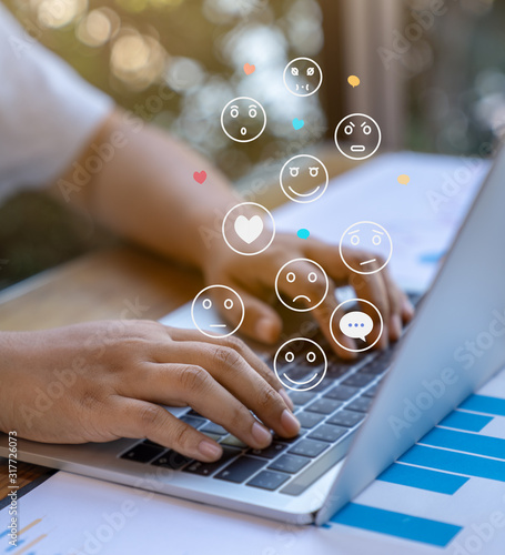 Businessman using a social media marketing concept on laptop computer with notification icons of like, chat, message and comment above laptop keyboard.