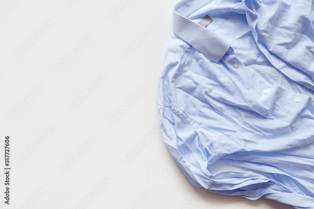 Fototapeta premium Blue cotton wrinkled and rumpled shirt on white. Washed shirt after tumble dryer