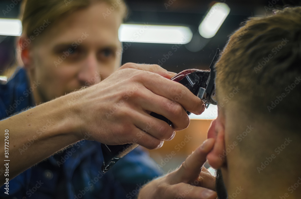 Fototapeta premium Barber shaves his hair at the client. Close-up