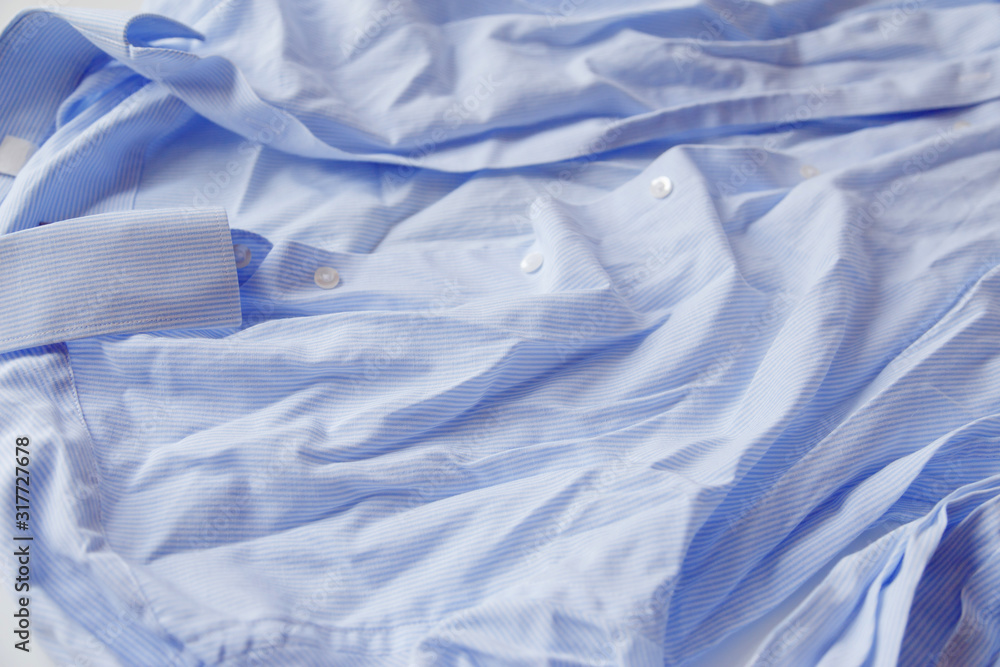 Obraz premium Blue cotton wrinkled and rumpled shirt on white. Washed shirt after tumble dryer