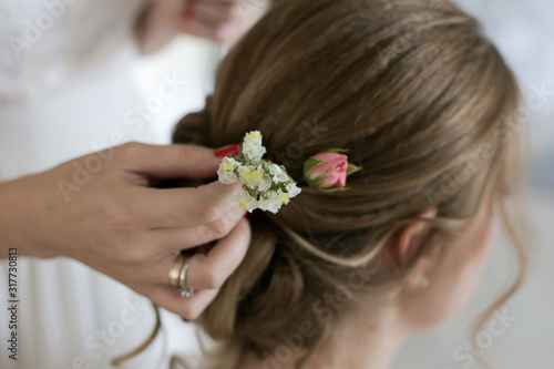 bridesmaid inserts flowers into bride's hair