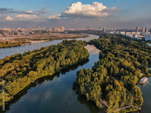Aerial photo of Moscow river and beautiful green nature around. Summer city in the background.