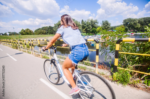 Fototapeta Naklejka Na Ścianę i Meble -  Pretty Woman Having Fun Riding Bicycle In Nature