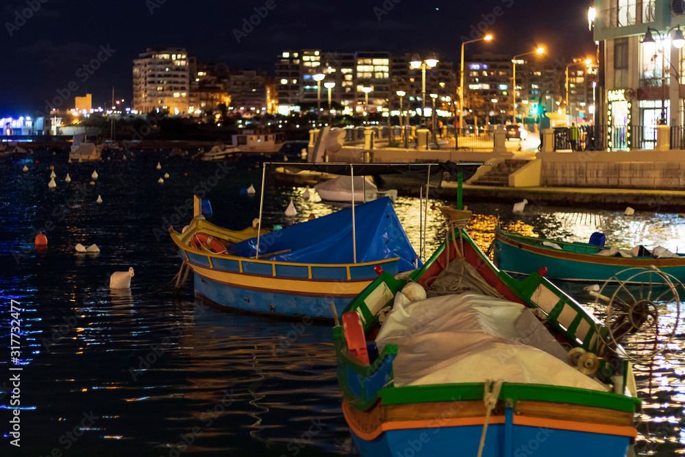 Colorful boats on the water of mediterranean sea bay in Malta at dark night with artificial lights