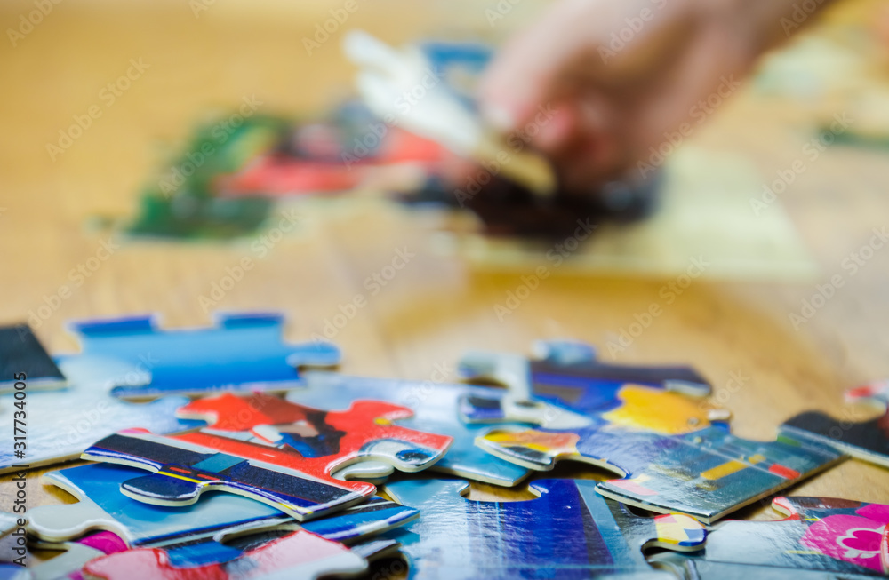 Close-up of a little five-year-old girl hand jigsaw puzzle with her favorite characters Close-up of a little five-year-old girl hand jigsaw puzzle with her favorite characters