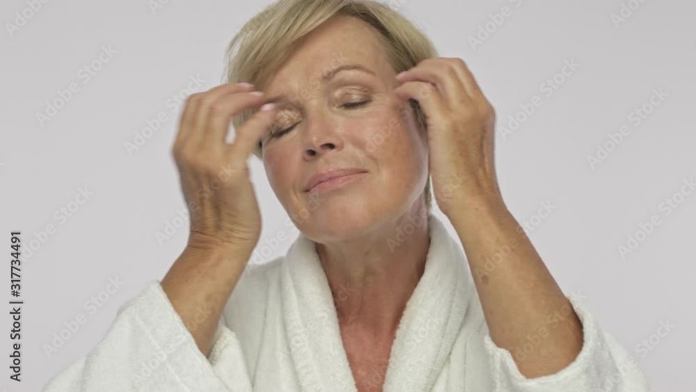 A pretty adult woman with short blond hair wearing white housecoat is touching her hair while making natural hair style isolated over white background A pretty adult woman with short blond hair wearing white housecoat is touching her hair while making natural hair style isolated over white background