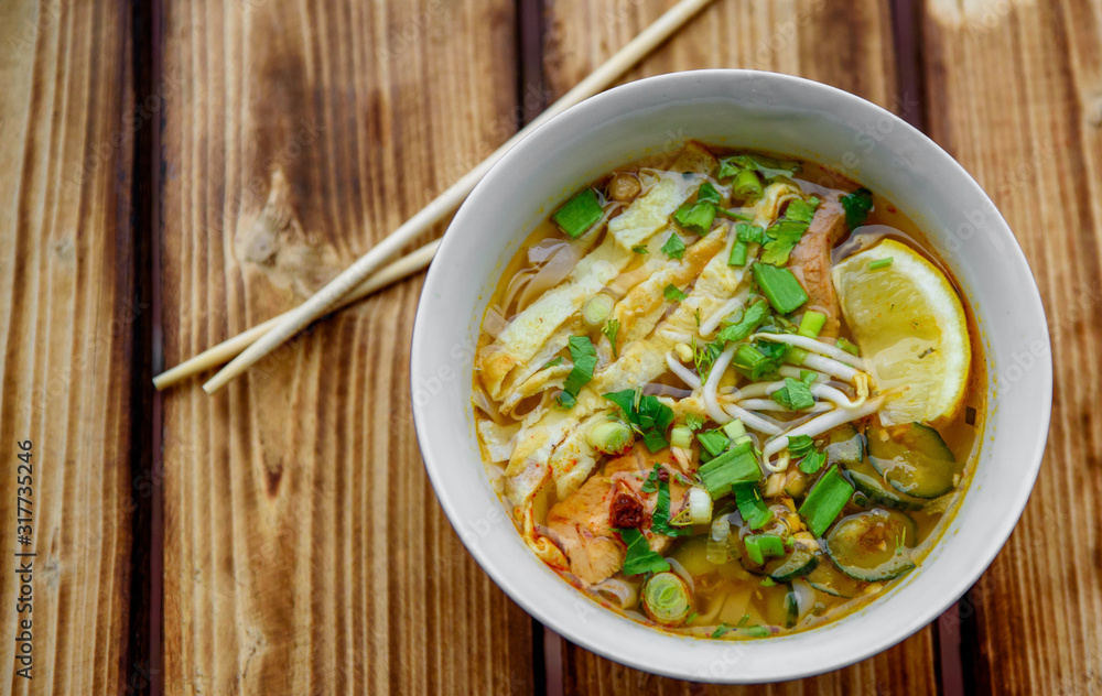 Spicy asian soup in bowl on wooden table background Spicy asian soup in bowl on wooden table background