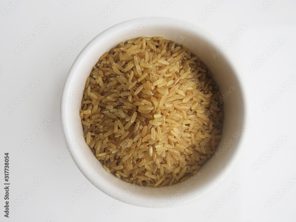 Organic raw Brown Rice in a white bowl on white background, top view. Integral Wholegrain. Organic raw Brown Rice in a white bowl on white background, top view. Integral Wholegrain.