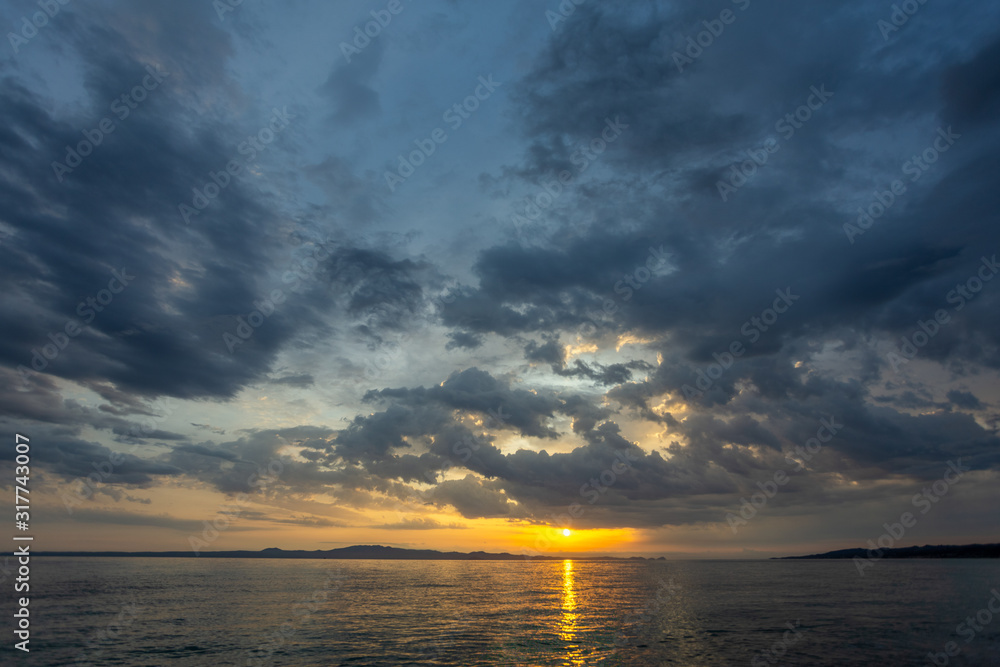 Beautiful dramatic early morning sunrise landscape. Cloudy sky and sunny water of Aegean sea in Greece, Chalkidiki. Horizontal color photography.