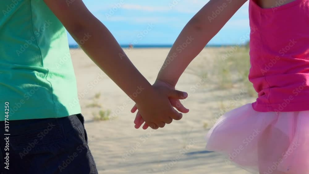 Close up of children holding hands on the beach. Little boy and girl holding hands on the background of sea shore Close up of children holding hands on the beach. Little boy and girl holding hands on the background of sea shore