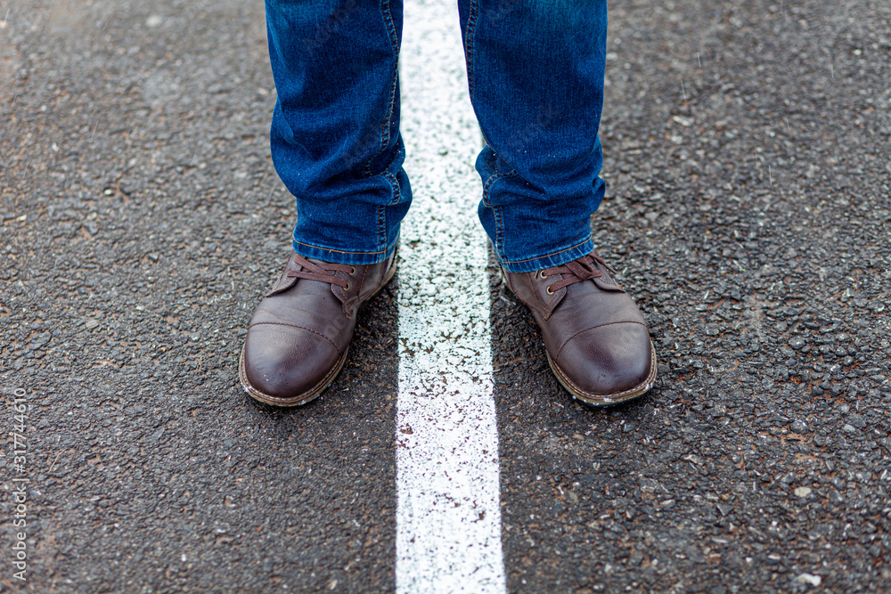 Men's feet in brown shoes on middle of road roadmap road lines brown legs straight line white line
