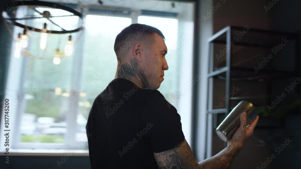 Tracking arc shot of young tattooed waiter showing tricks with cocktail shaker and flipping it, 360 degree Tracking arc shot of young tattooed waiter showing tricks with cocktail shaker and flipping it, 360 degree