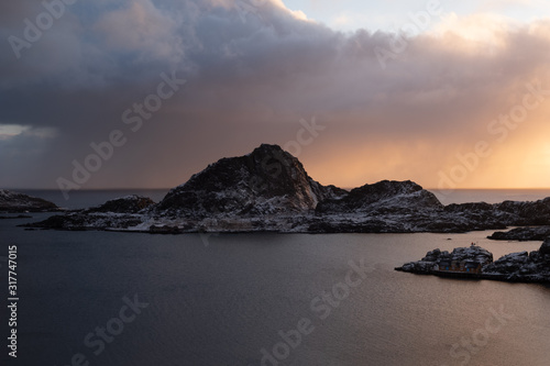 typical lofoten islands view. fishin town with mountains in backround. famous archipelago in north of norway. winter in wonderland. sunrise over typical and famous red cabins and fishermen's cabins.