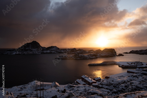 typical lofoten islands view. fishin town with mountains in backround. famous archipelago in north of norway. winter in wonderland. sunrise over typical and famous red cabins and fishermen's cabins.