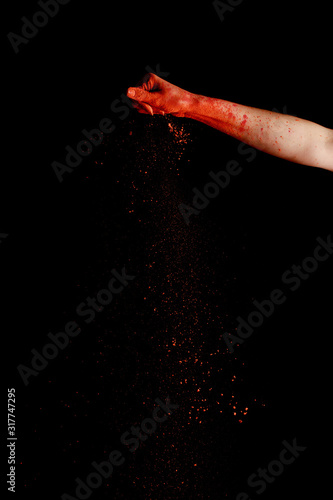 female hand with red colorful holi paint powder on black background