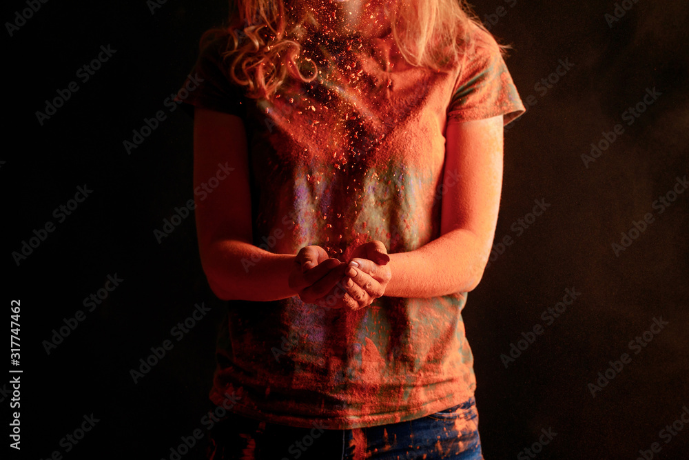 Φωτογραφία cropped view of woman with orange colorful holi paint powder isolated on black