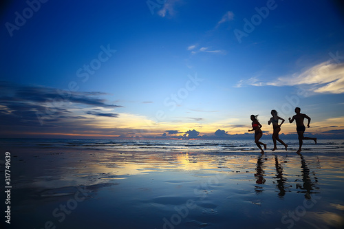 silhouettes of athletes running along the beach / sports summer in the warm sea, healthy rest, sports activity, summer vacation © kichigin19