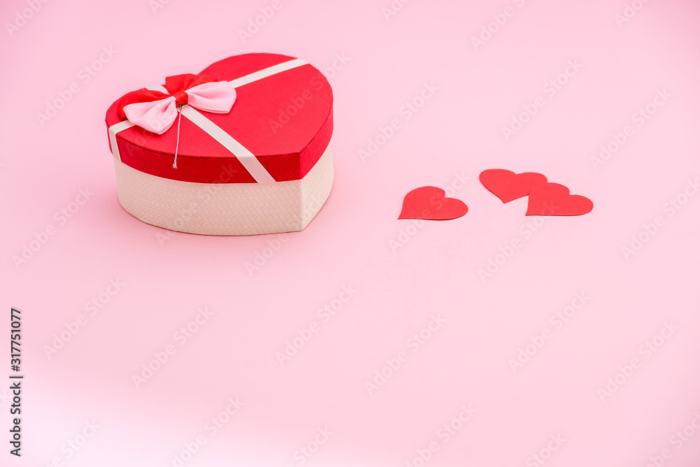 Heart shaped gift box and red paper hearts on pink pastel background. Valentines day concept Heart shaped gift box and red paper hearts on pink pastel background. Valentines day concept