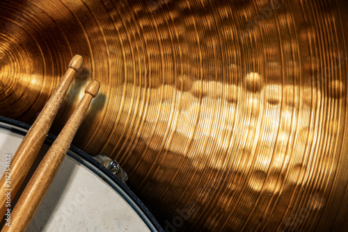 Obraz na płótnie Close-up of two wooden drumsticks on an old metallic snare drum and golden colored cymbal with copy space