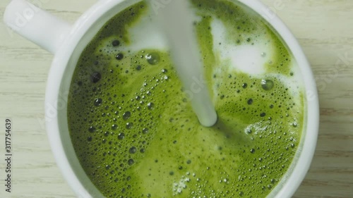 Pouring milk into green matcha tea, slow motion