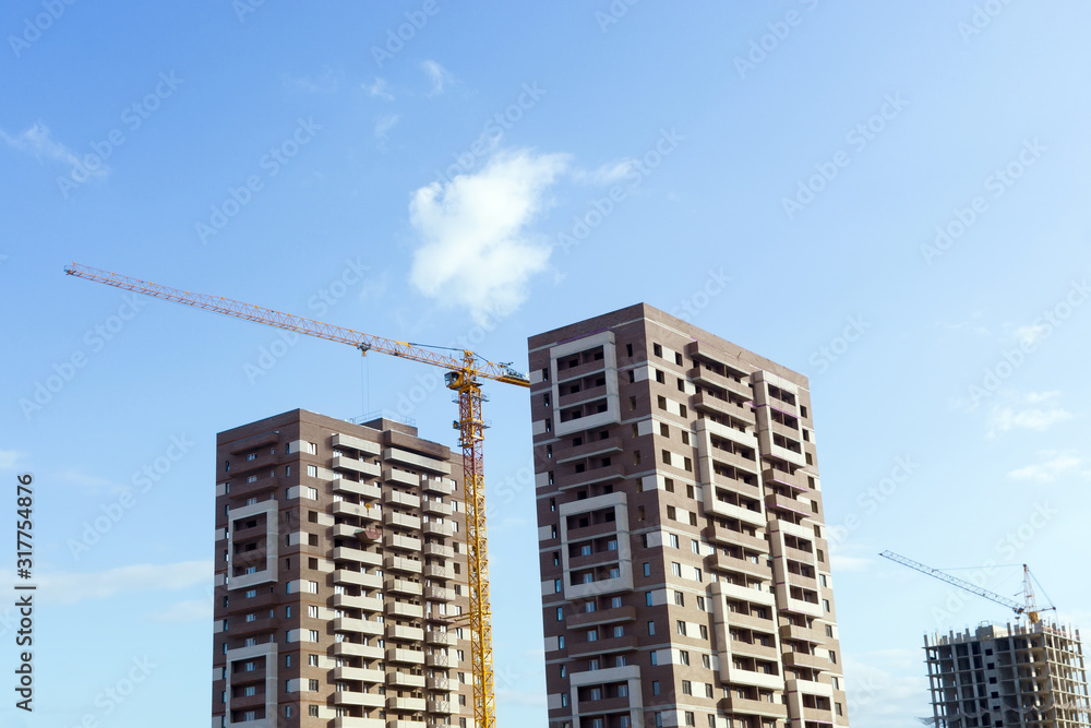 houses under construction against the blue sky. construction crane selective focus. free space for copy space