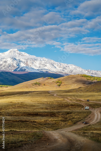 UAZ off-road vehicles drive along a field road in the Kurai steppe. Autumn in the Altai mountains. Russia