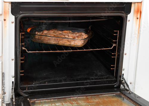 Open oven with cooked chicken meat