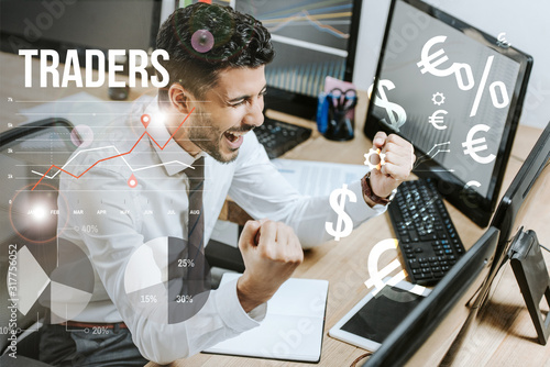 Φωτογραφία happy bi-racial man showing yes gesture near computers and traders letters