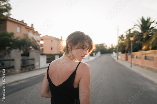 girl walks through the city streets at sunset