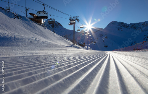 ski resort, snow corduroy, unrolled, snow, which only passed the snowgroomer. Prepared snowcat trail on a background of mountains. ski track with funicular and prepared track