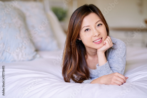 Young Asian woman with perfect skin lying on her bed