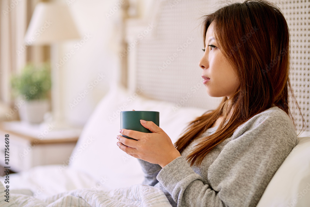 Young Asian woman drinking coffee in her bed at home Young Asian woman drinking coffee in her bed at home