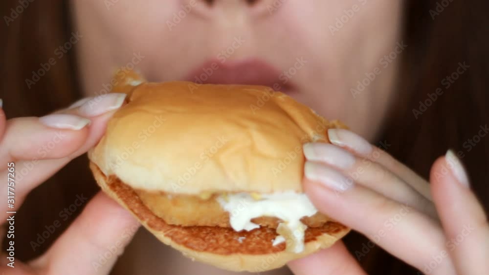 Woman eating a hamburger. Mouth and fast food close-up Woman eating a hamburger. Mouth and fast food close-up
